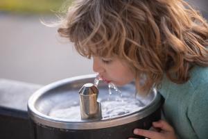 Child drinking from outdoor water fountain at school | Image Credit: © Volodymyr - stock.adobe.com