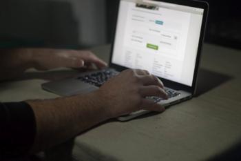 Person using laptop in dark room. Security, Crime.