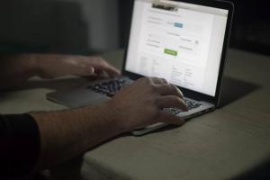 Person using laptop in dark room. Security, Crime.
