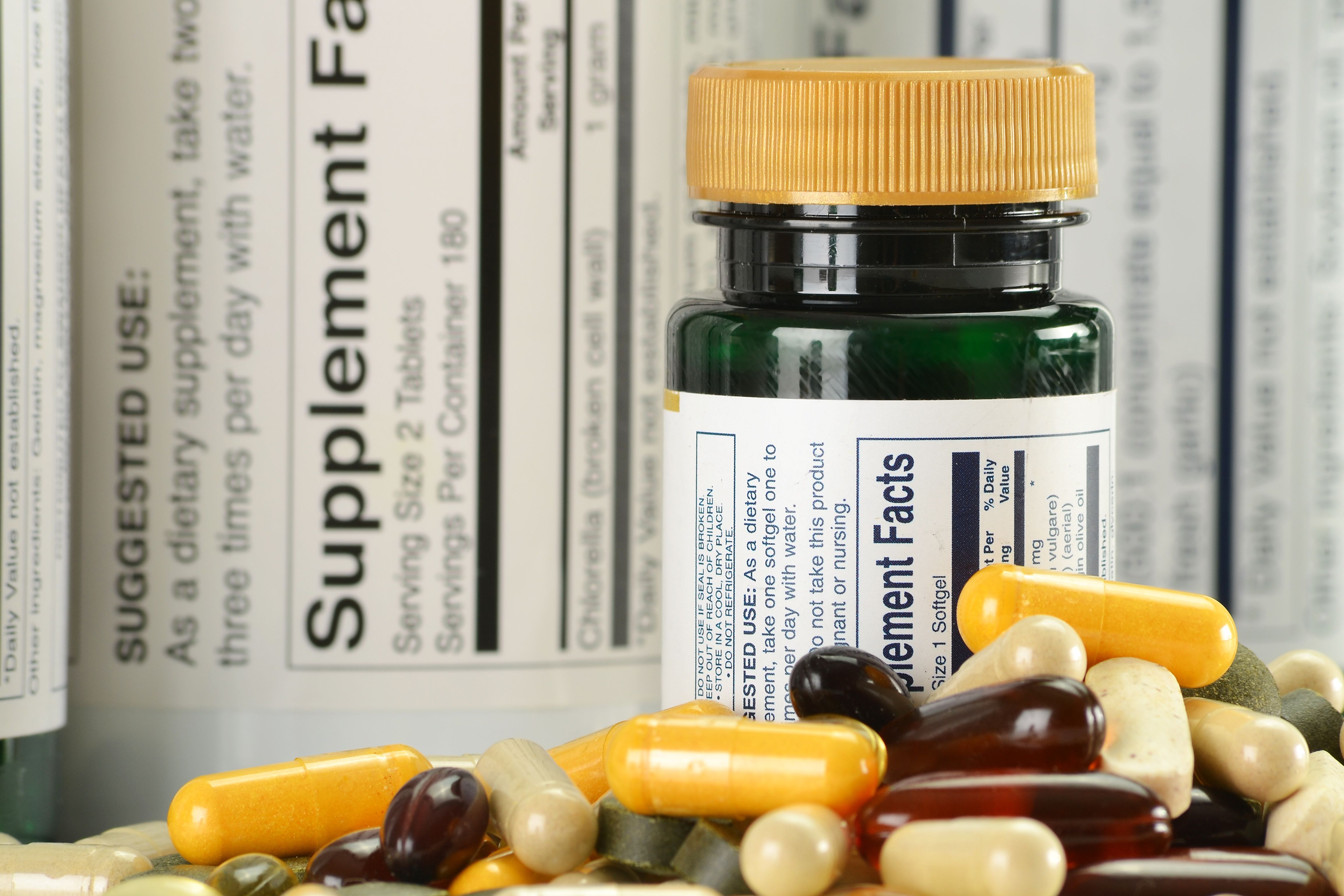 Composition with dietary supplement capsules and containers - Image credit: monticellllo | stock.adobe.com