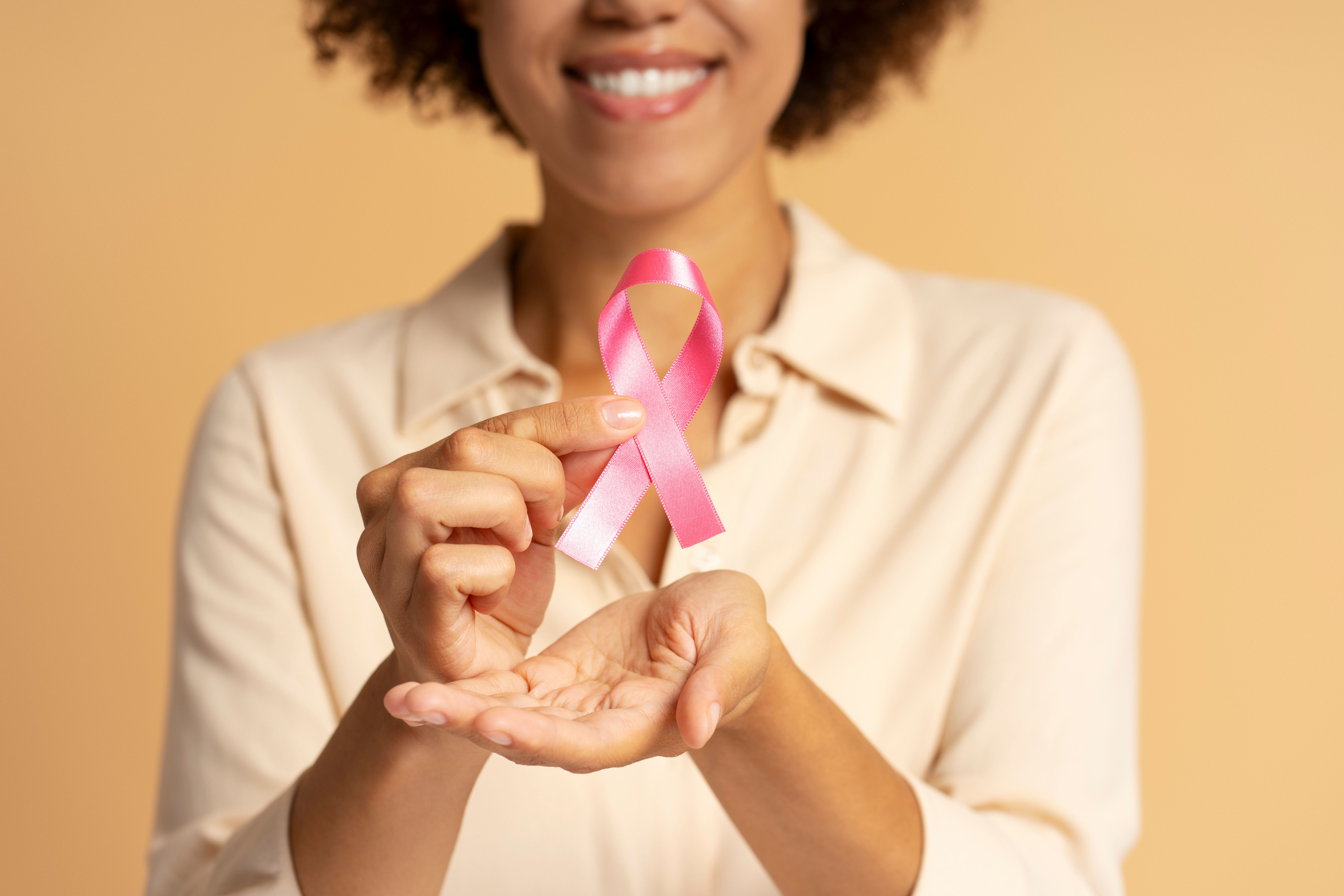 Black woman holding pink ribbon for breast cancer awareness -- Image credit: Maria Vitkovska | stock.adobe.com