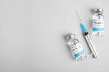 Vials with coronavirus vaccine and syringe on light background, flat lay- Image credit: New Africa | stock.adobe.com