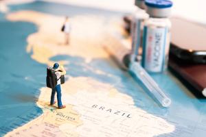 Miniature traveler looking for vaccine passport. concept of vaccination certificate and safe travel under virus pandemic. | Image Credit: Yuan | stock.adobe.com