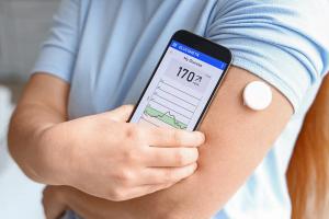 Woman with glucose sensor using mobile phone for measuring of blood sugar level, closeup - Image credit: Pixel-Shot | stock.adobe.com