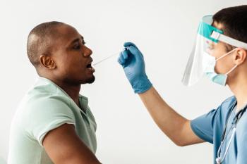 Fight against virus covid-19, check before vaccination. Young doctor in uniform, mask and protective gloves takes covid test from african american patient at table with syringes, ampoules, copy space - Image credit: Prostock-studio | stock.adobe.com