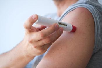 An anonymous man injecting a treatment such as insulin or adalimumab, etanercept or epinephrine into his shoulder. It is a white pen injector with red head for health care. - Image credit: LaMorenita | stock.adobe.com