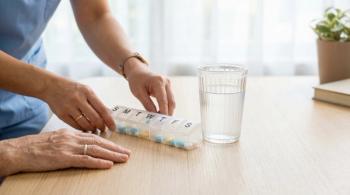 Pill organizer prepared by caregiver hands for senior patient on wooden table next to glass of water, geriatric healthcare and daily medication management concept - Image credit: CK Studio | stock.adobe.com