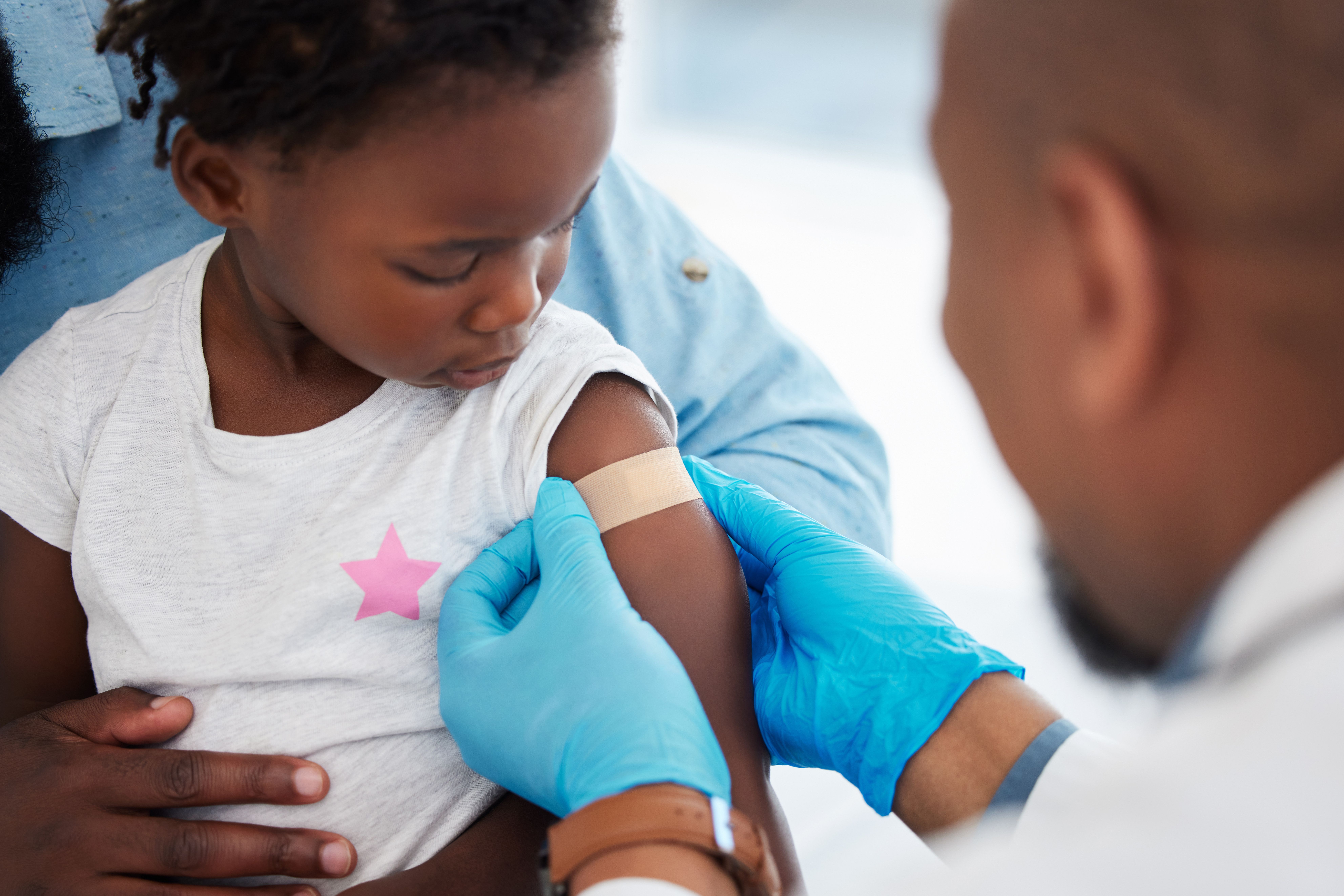 Child, healthcare vaccine and doctor with plaster for skin protection after injection appointment. Black kid and medical worker with bandage for healing of wound from needle medicine immunity - Image credit: Nina Lawrenson/peopleimages.com | stock.adobe.com