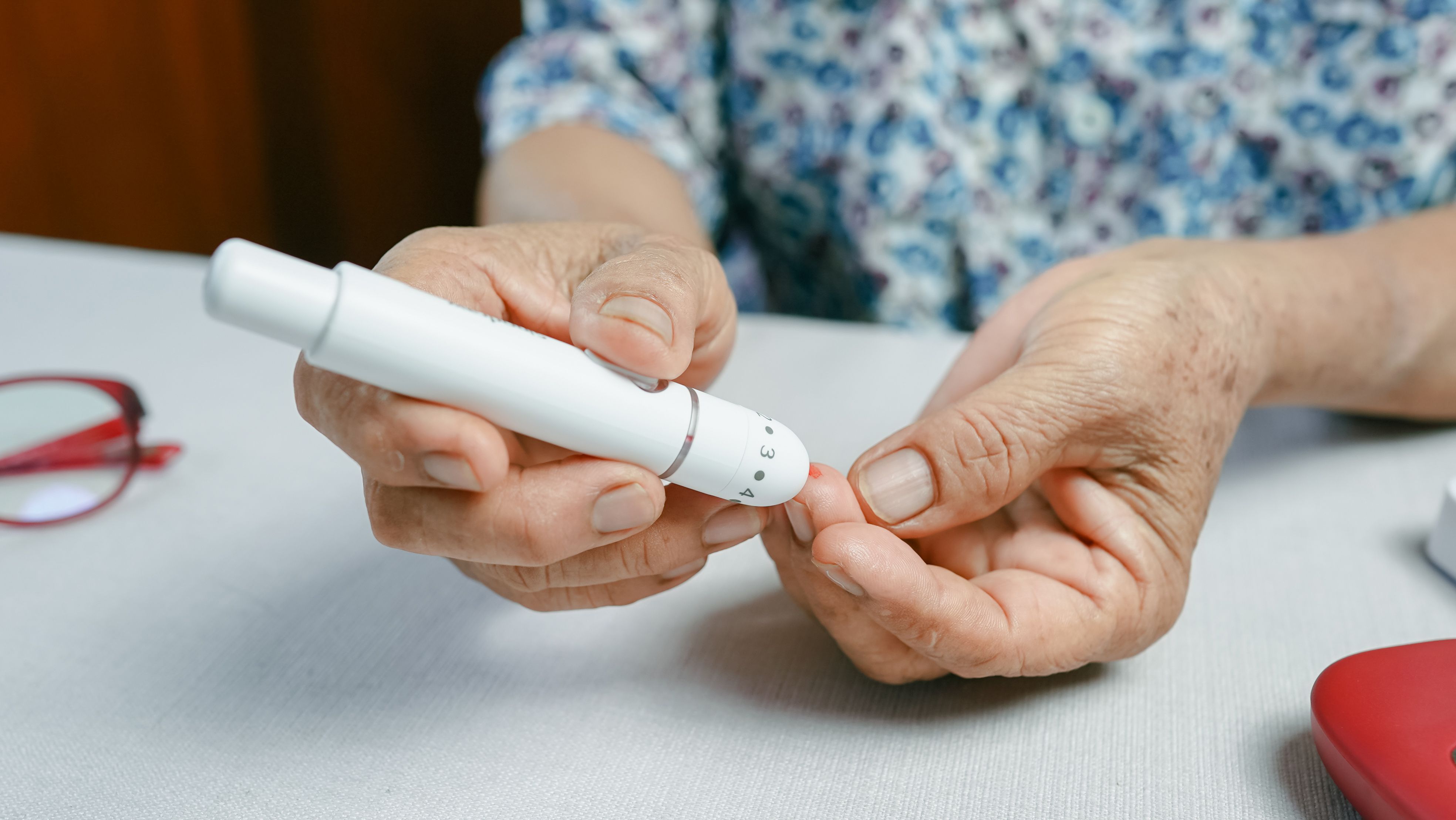 Close up of senior woman using lancet device for finger prick blood test, showing diabetes monitoring and glucose control. Elderly healthcare and chronic disease management concept. Image credit: Oporty786 | stock.adobe.com
