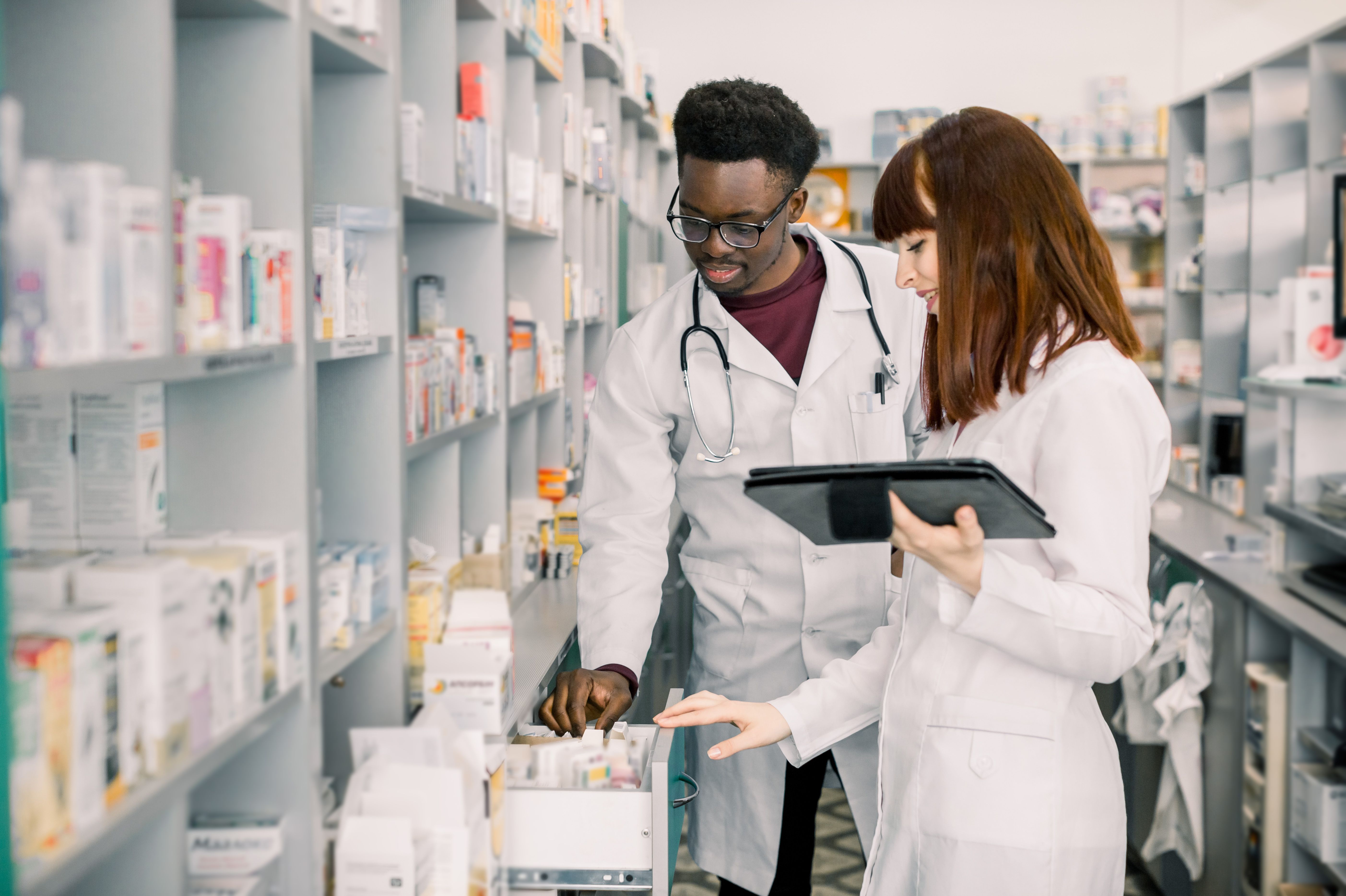 Portrait of two smiling friendly multiethnical pharmacists working in modern pharmacy and making order for medicines in distribution company | Image Credit: sofiko14 | stock.adobe.com