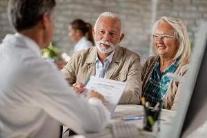 Happy senior couple going through medical insurance paperwork with a doctor - Image credit: Drazen | stock.adobe.com