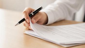 Close-up of a person holding a luxury pen while flipping through pages of a business contract document on a wooden desk | Image Credit: © Jahanzaib - stock.adobe.com
