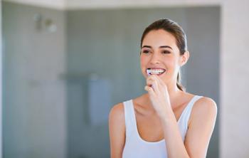 Toothbrush, toothpaste and woman brushing teeth in bathroom for health, happiness and wellness in morning. Girl, cleaning mouth for dental care and oral hygiene or smile in home with mockup space - Image credit: Jadon B/peopleimages.com | stock.adobe.com