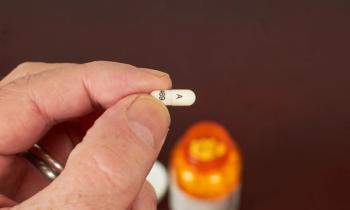 Man holding gabapentin capsule -- Image credit: Lokelani | stock.adobe.com