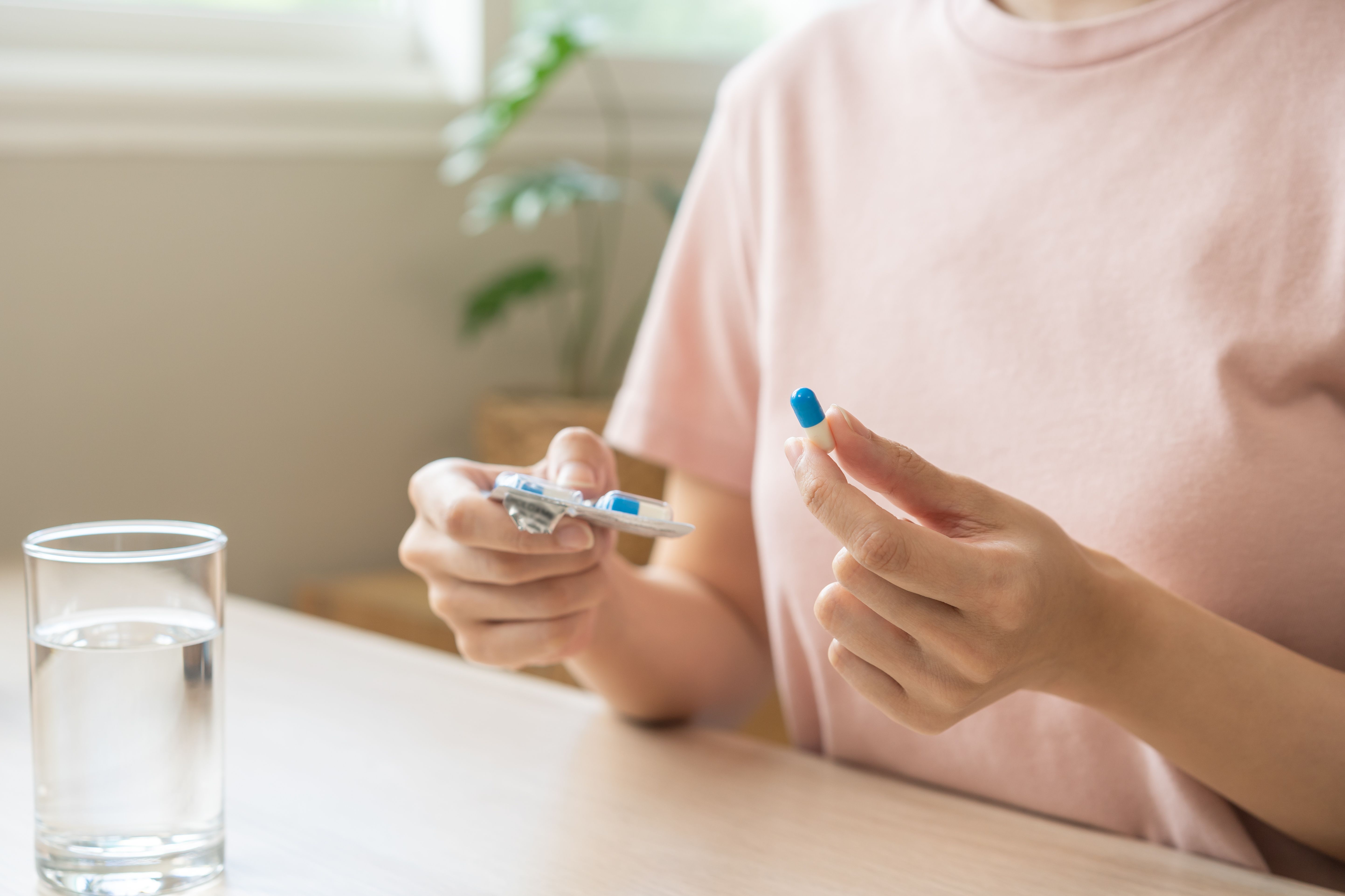 Woman holding antidepressants -- Image credit: KMPZZZ | stock.adobe.com