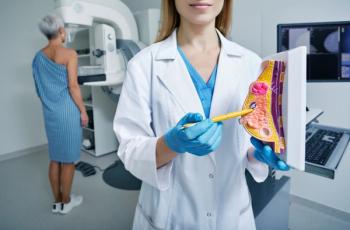 Health care professinal shows model of breast with tumor -- Image credit: Peakstock | stock.adobe.com