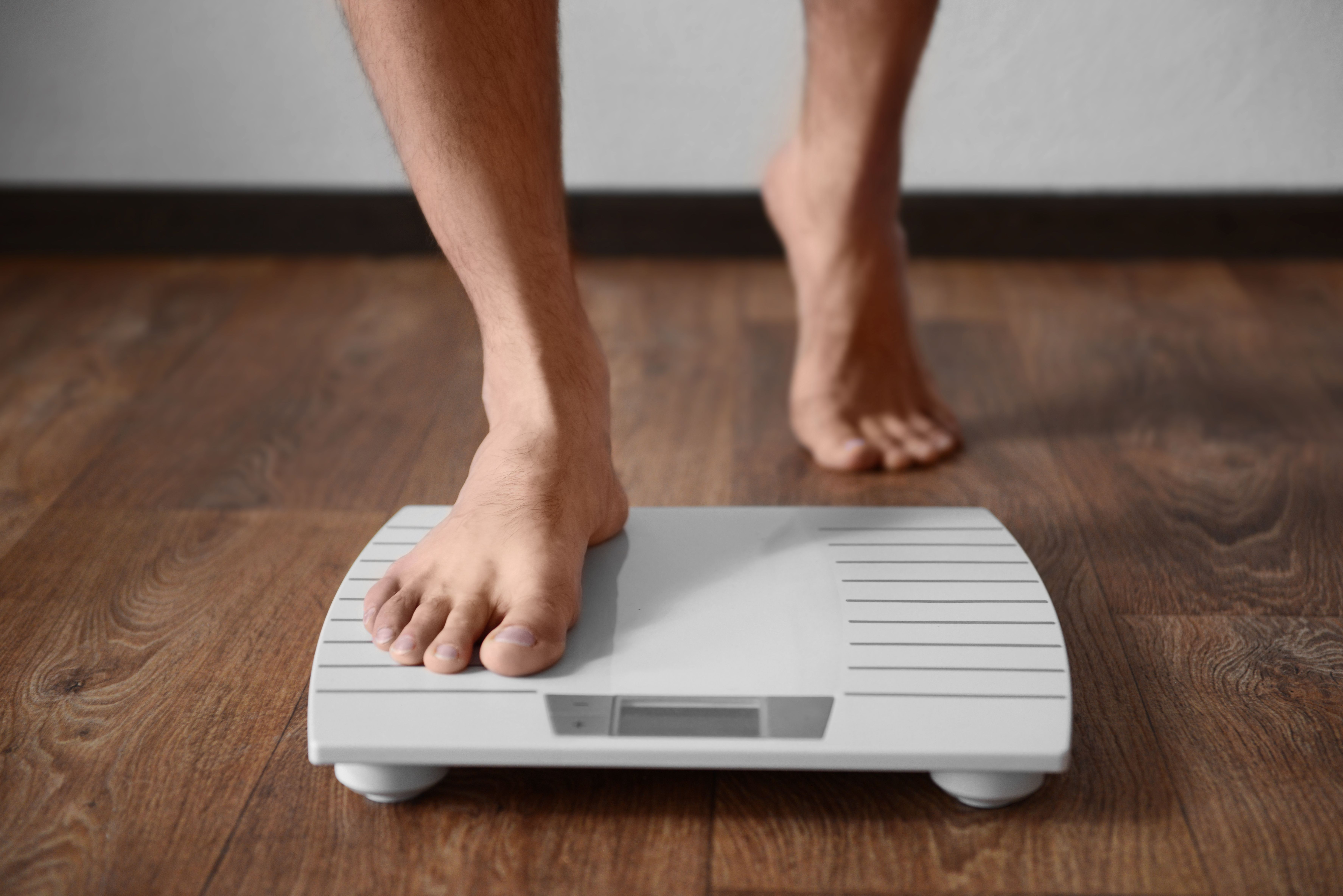 Teenager stepping on scale -- Image credit: Africa Studio | stock.adobe.com