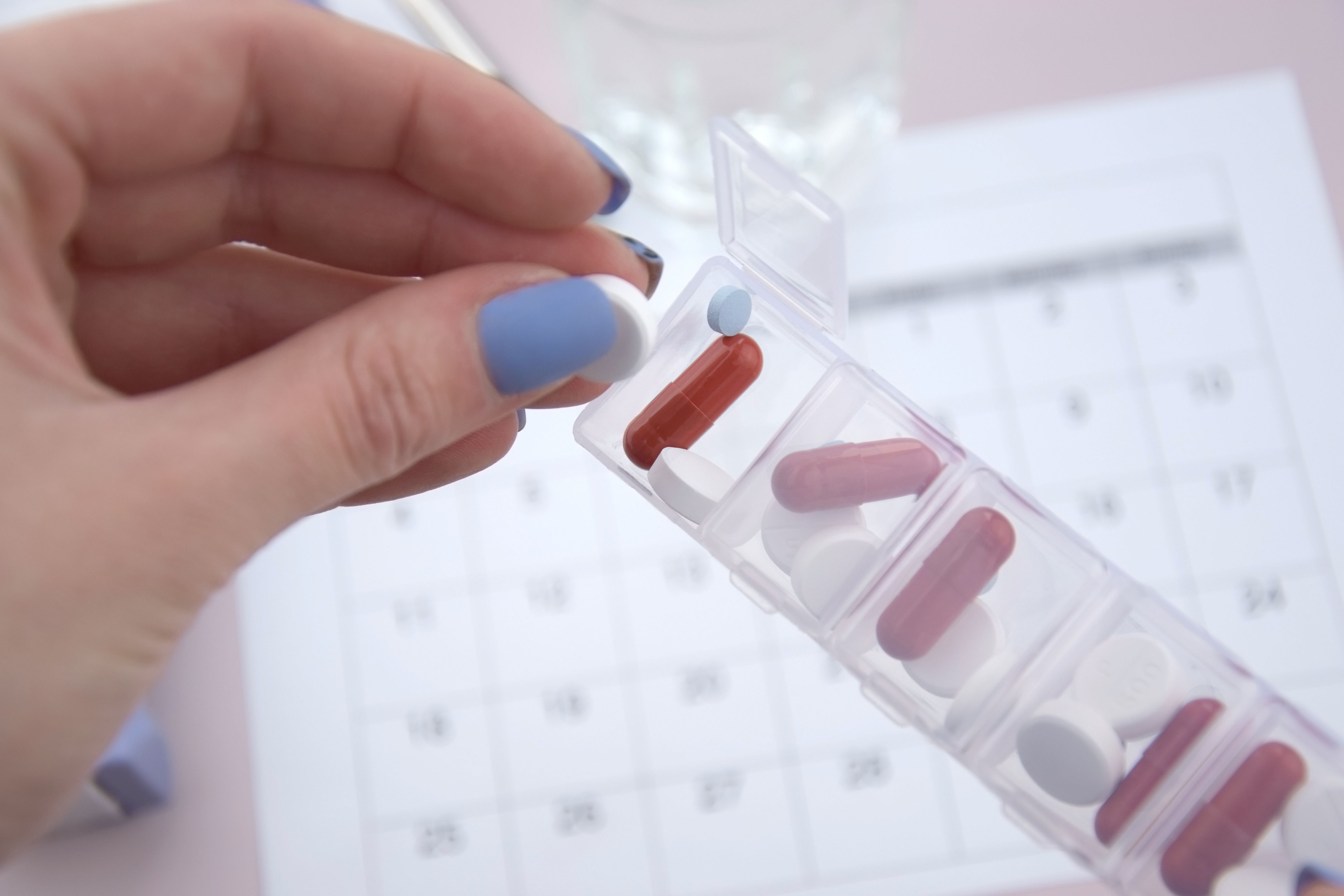 Woman taking prescription medication from daily pill organizer