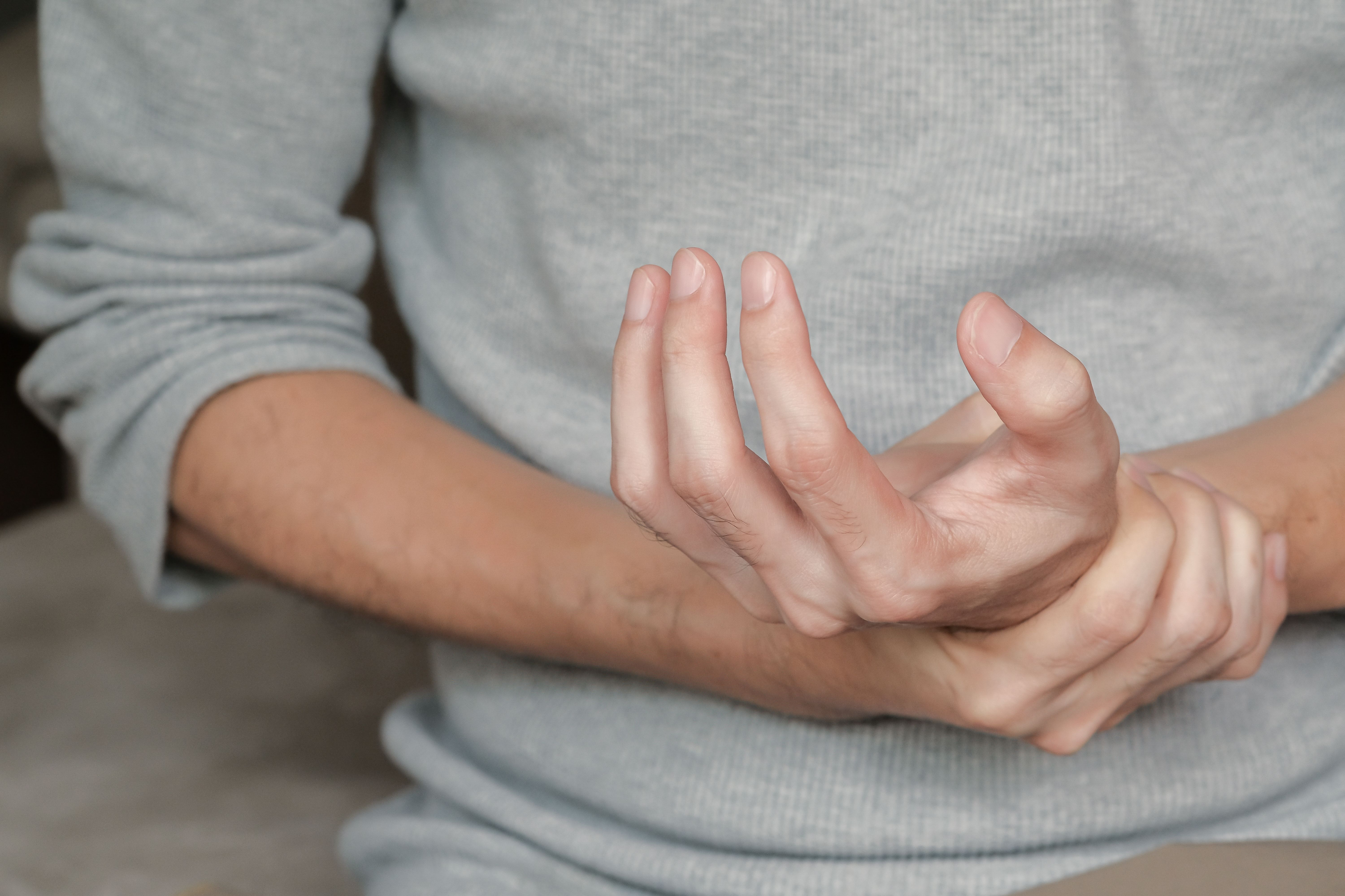 Man holding hand with muscle weakness, numbness and paralysis symptoms due to Guillain Barre syndrome