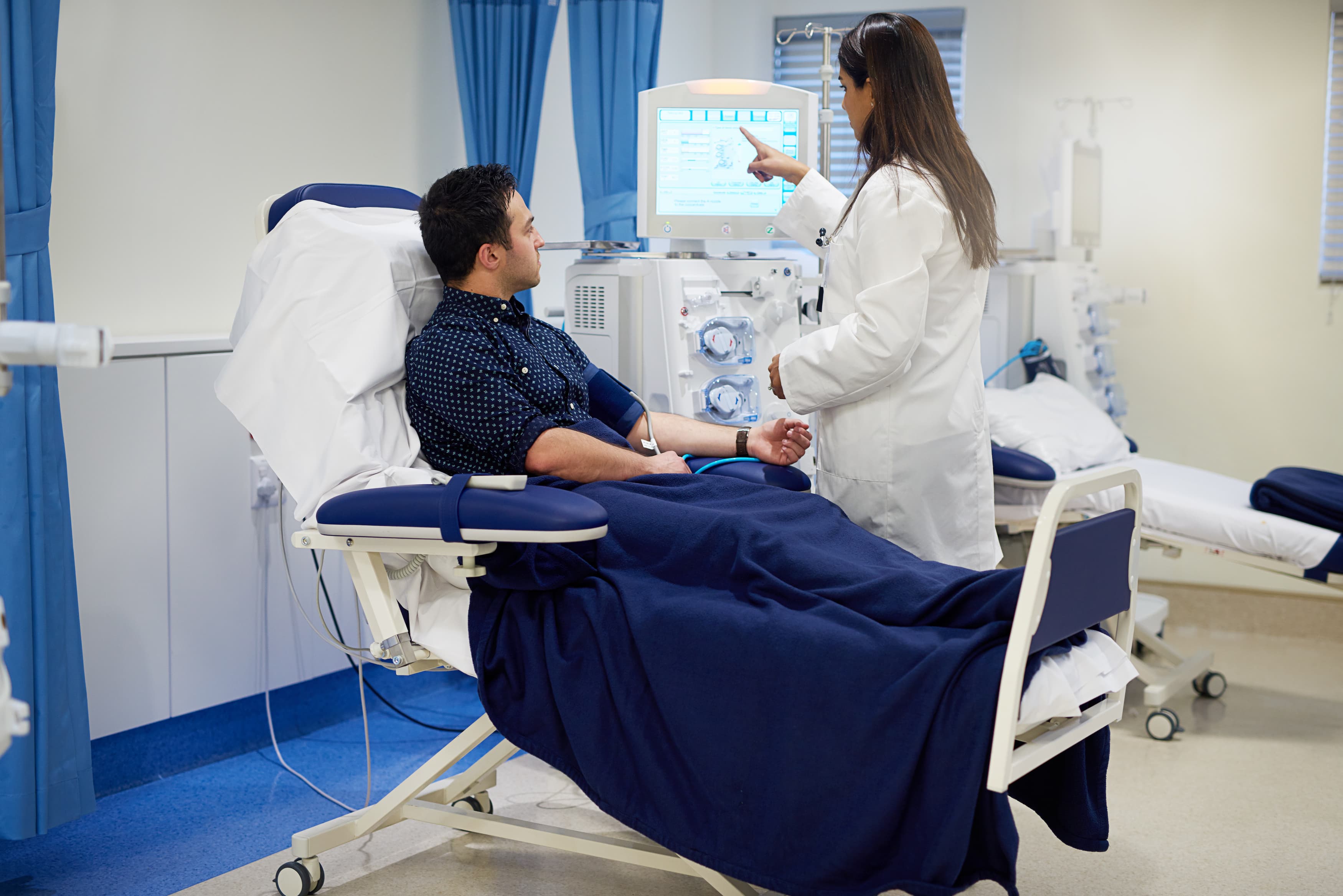 Man, doctor and dialysis machine in hospital for kidney assessment, organ fail and medical diagnosis for health. Patient, woman and screen exam for Nephrology, filter blood and hemodialysis treatment