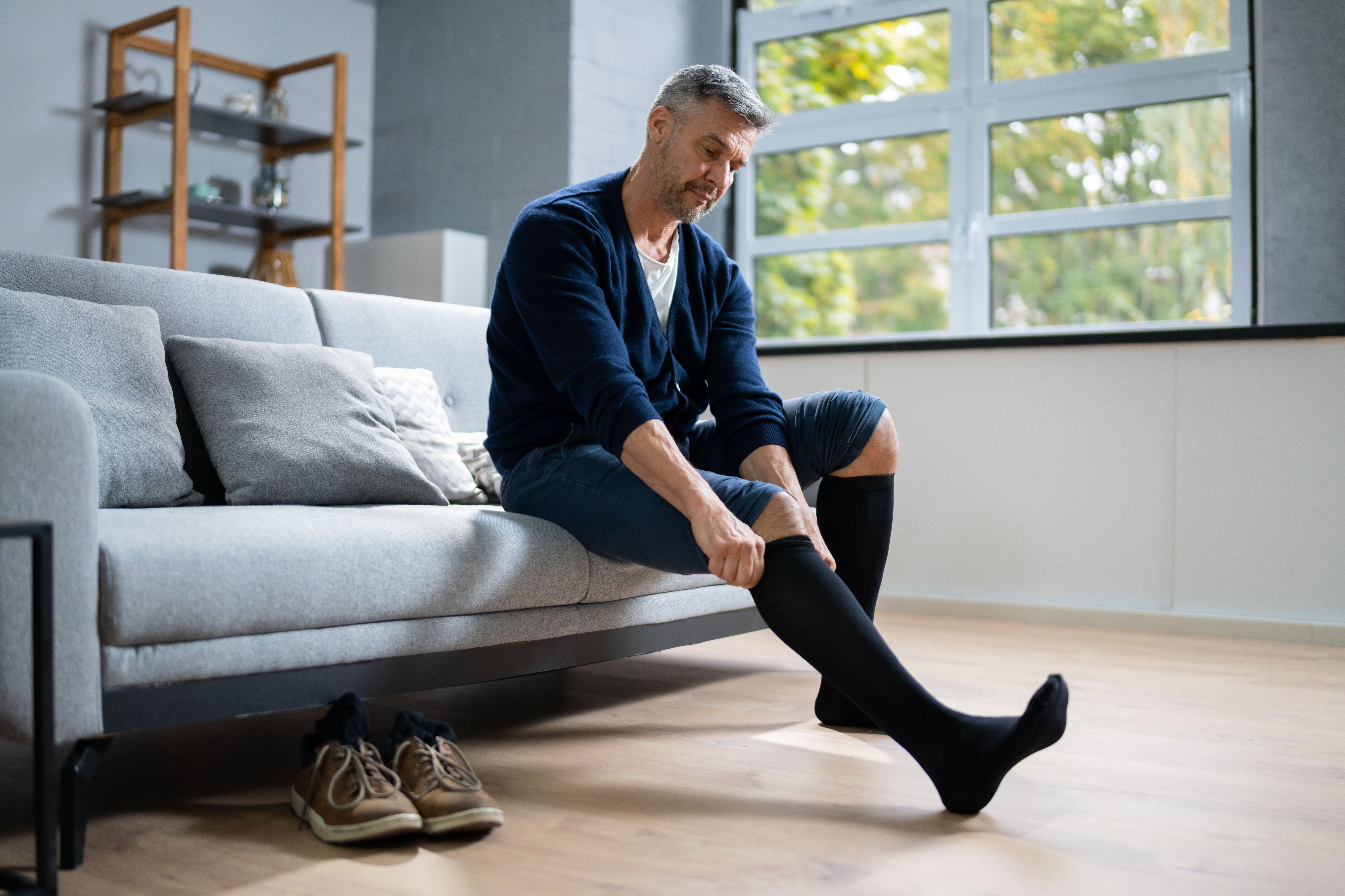 Man Putting On Medical Compression Stockings | Image Credit: Andrey Popov - stock.adobe.com