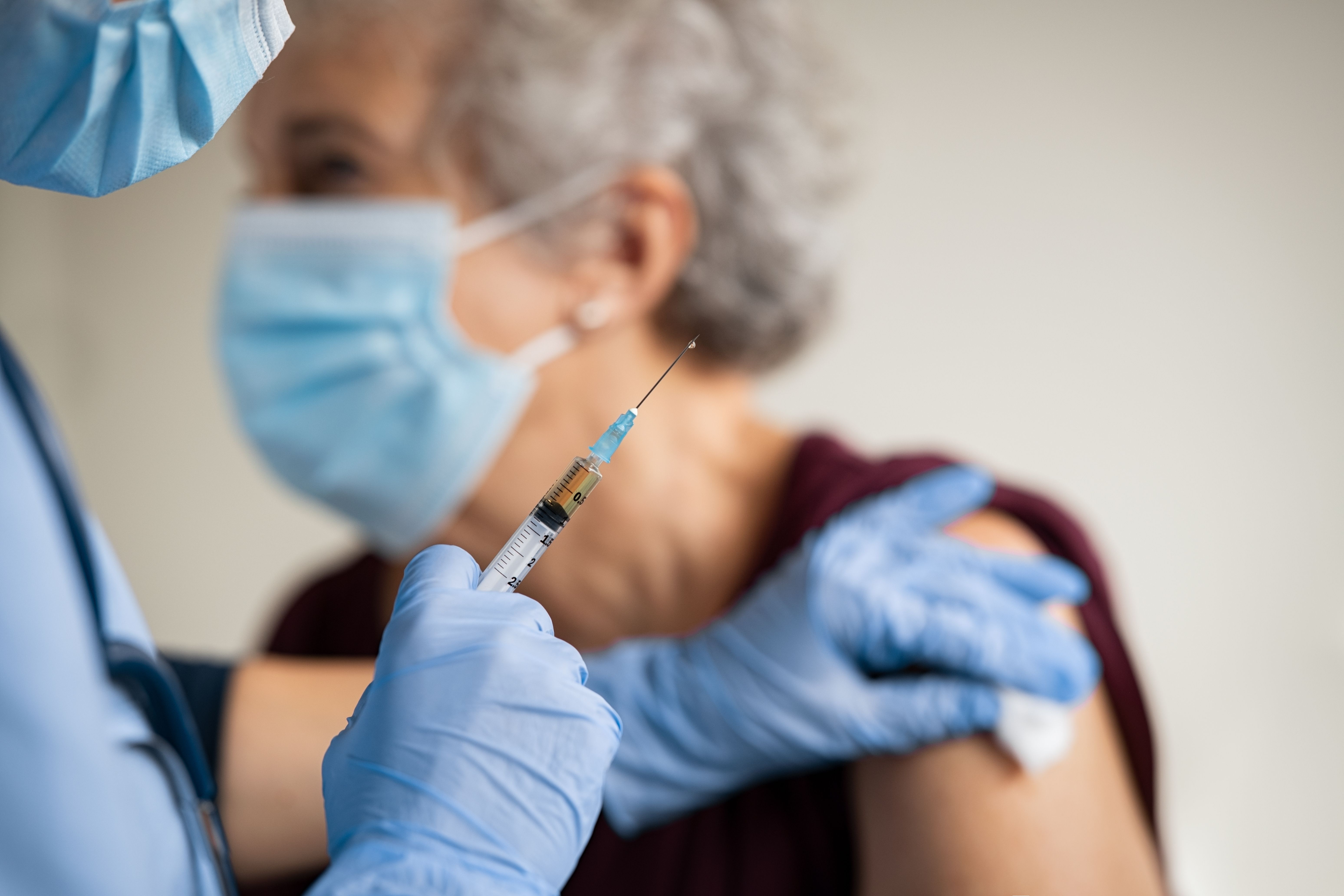 Pharmacist giving elderly patient a vaccine -- Image credit: Rido | stock.adobe.com