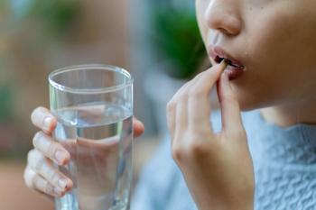 Close-up of woman taking a capsule with a glass of water, concept of health care, supplement intake, medication routine, or daily wellness and nutrition habi