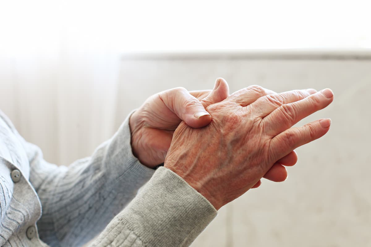 Elderly woman applying moisturizing lotion cream on hand palm, easing aches. Senior old lady experiencing severe arthritis rheumatics pains, massaging, warming up arm. 