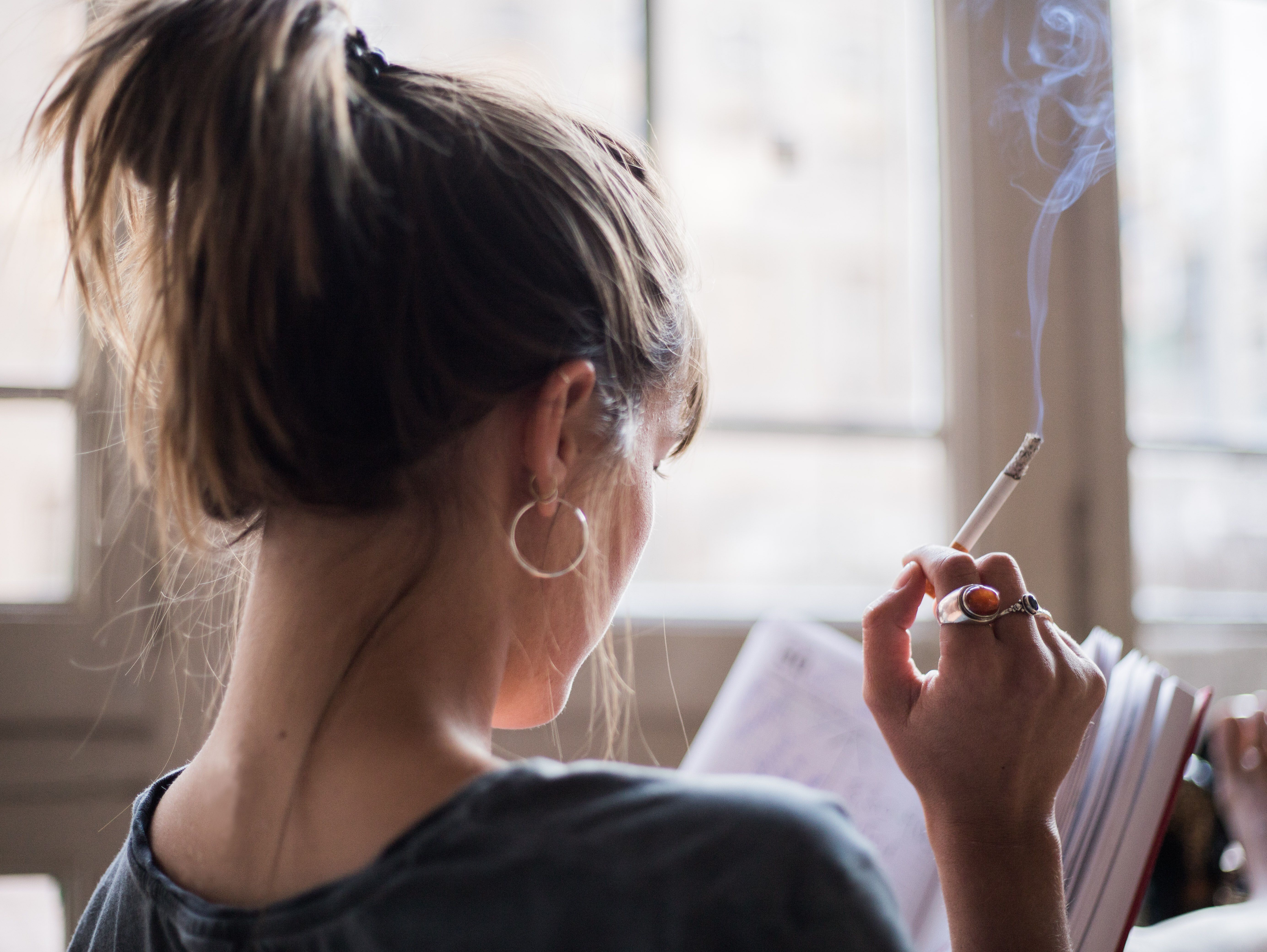 Woman smoking and reading | Image Credit: marc - stock.adobe.com