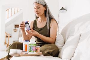 woman taking her medication while sitting on couch - Image credit: Drobot Dean | stock.adobe.com