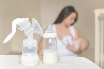 Manual breast pump and bottle with breast milk on the background of mother holding in her hands and breastfeeding baby. Maternity and baby care - Image credit: evso | stock.adobe.com