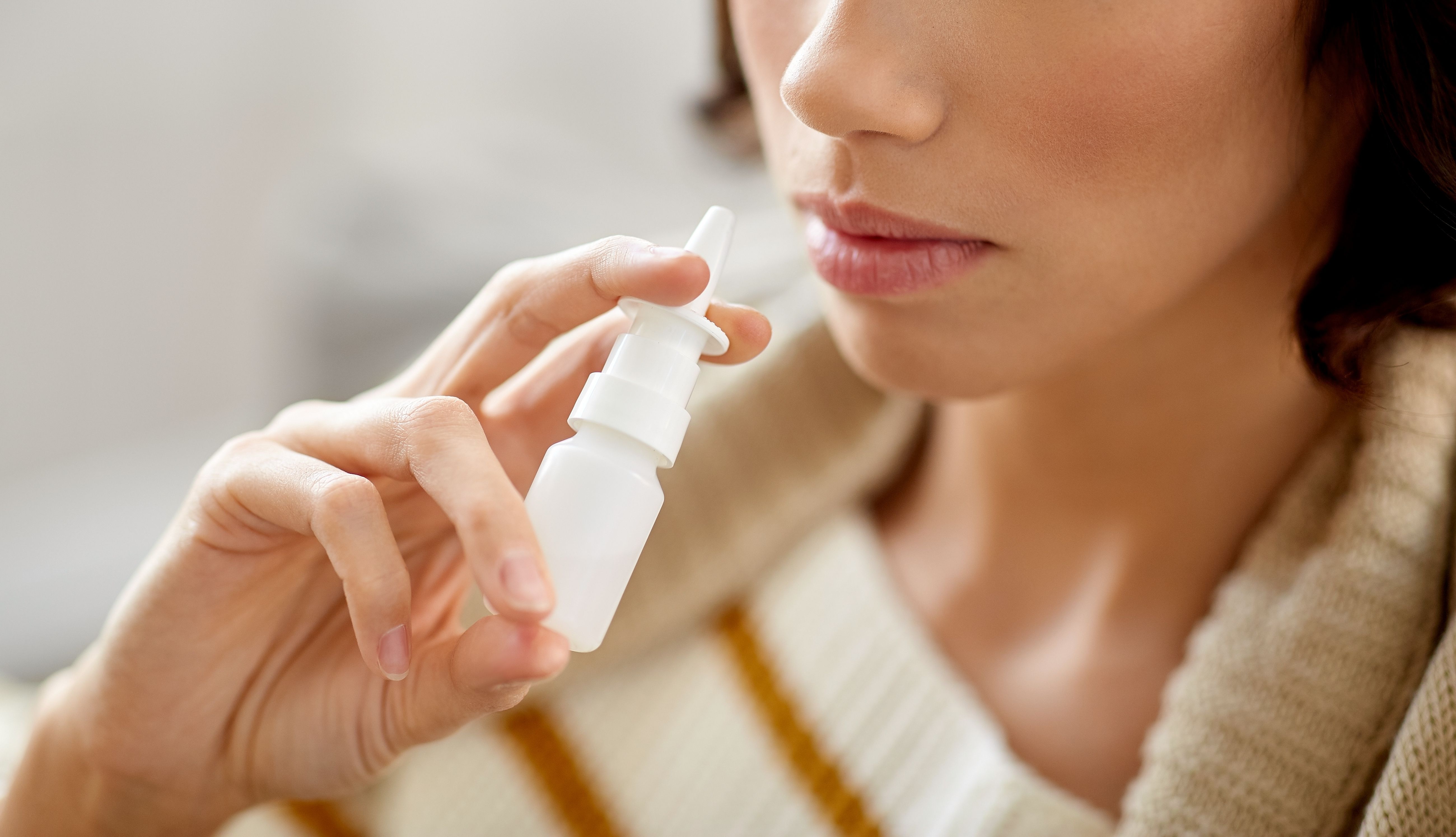 rhinitis, medicine and healthcare concept - close up of sick woman using nasal | Image Credit: Syda Productions | stock.adobe.comspray 