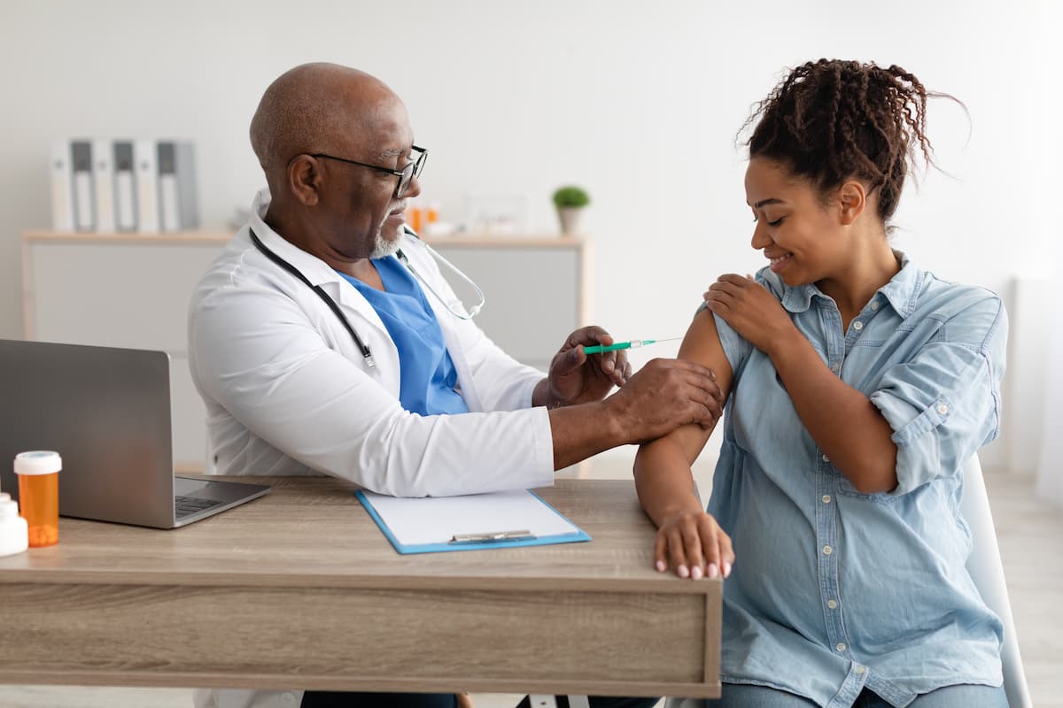 Smiling Pregnant Black Woman Getting Vaccinated In Doctor's Office