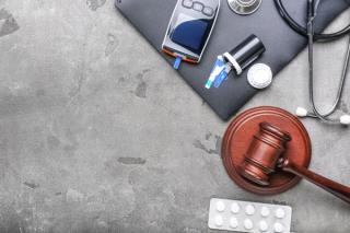 Judge gavel, pills, glucometer and stethoscope on grey background