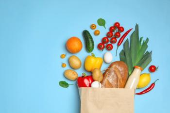 Shopping paper bag with different groceries on light blue background, flat lay.