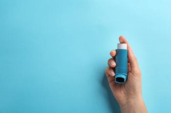 Woman holding asthma inhaler on color background, top view. | Image Credit: New Africa - stock.adobe.com