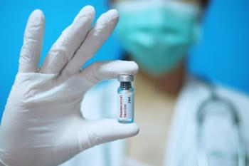 Surgical mask and white rubber gloves at a clinic, holding a glass bottle of 1 dose PCV vaccine with white background and red letters -nImage credit: Sirichai | stock.adobe.com