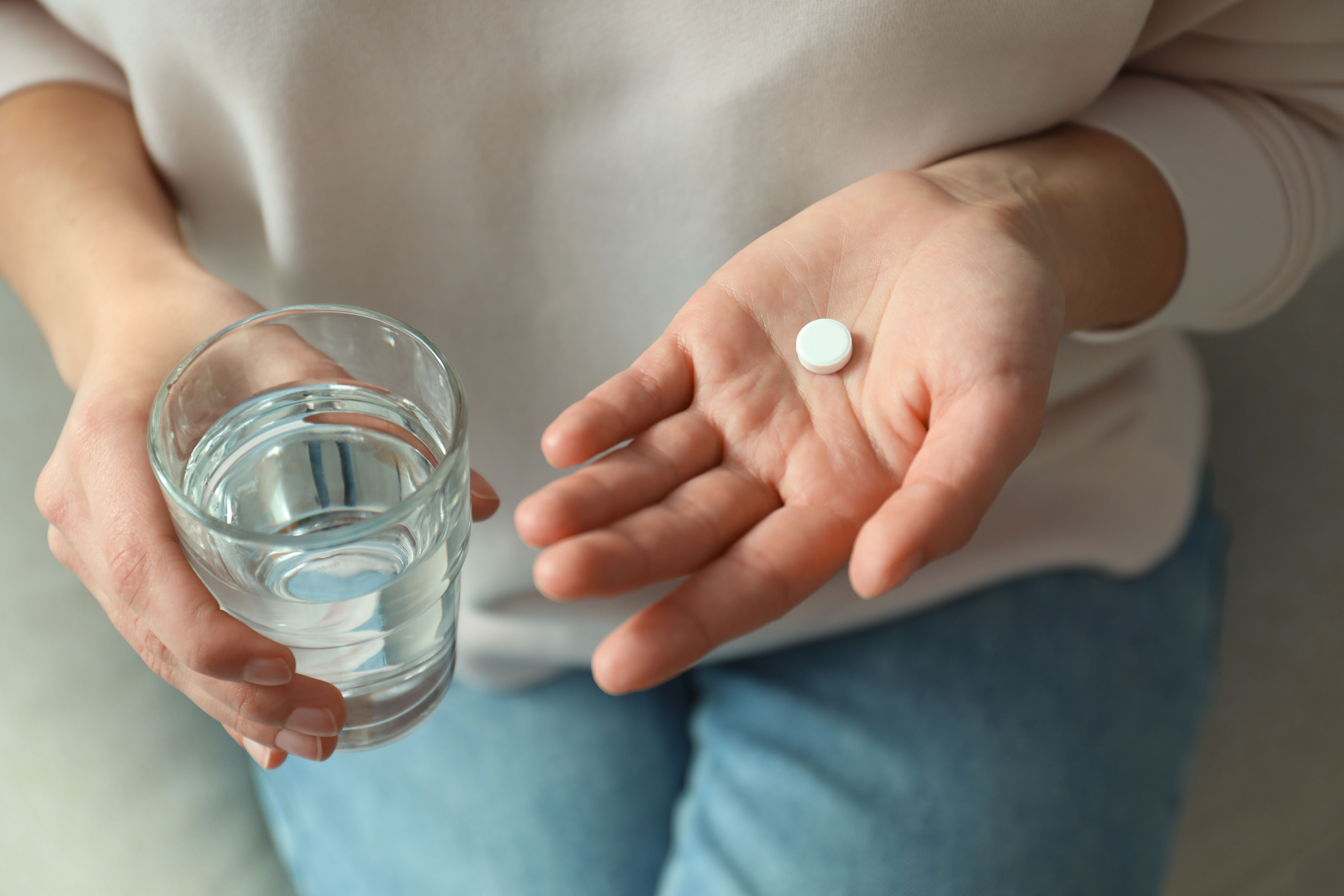 Patient taking oral tablet with water -- Image credit: New Africa | stock.adobe.com