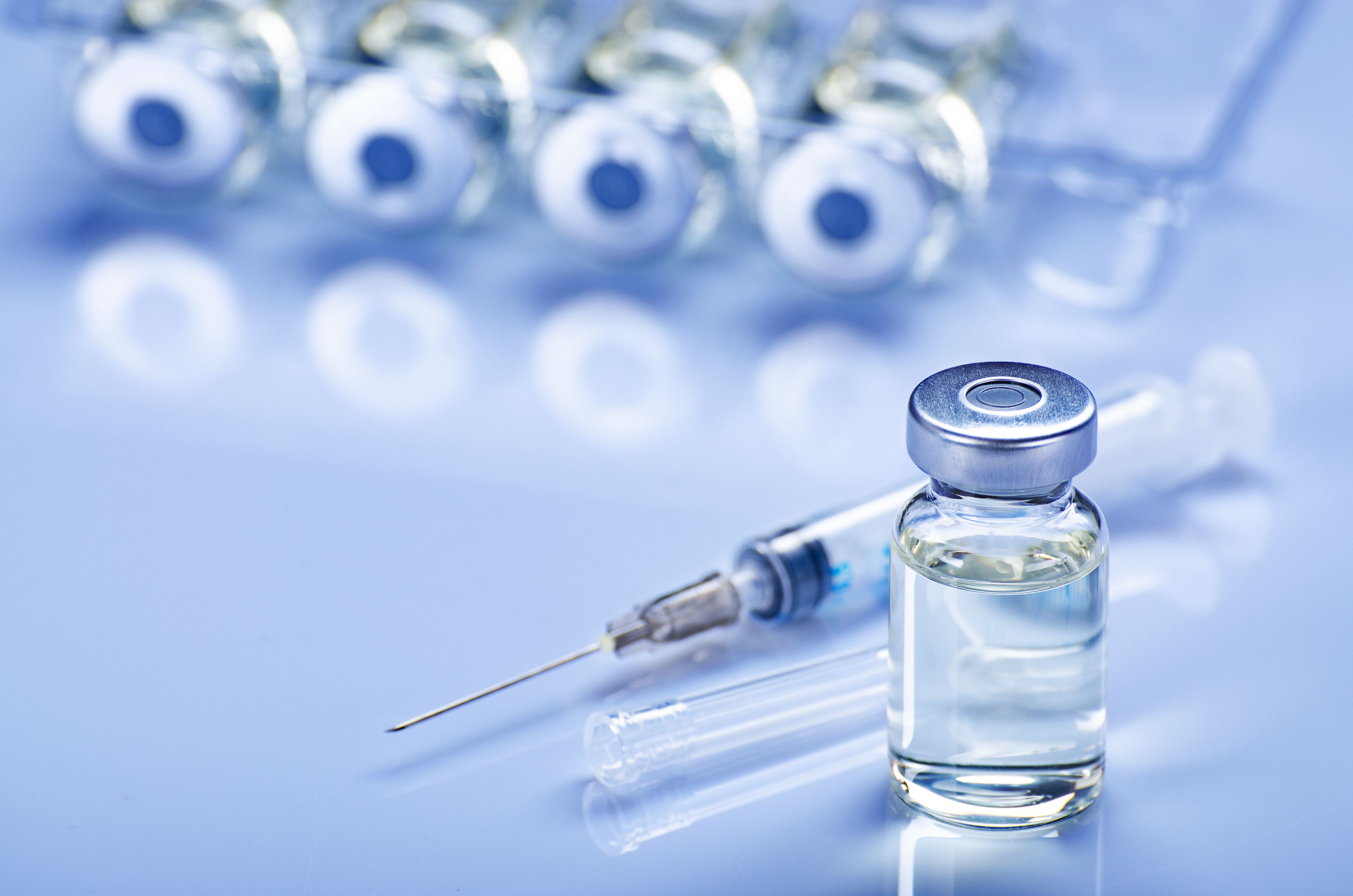 Single use syringe for injection treatment on medical table with vials of liquid drug doses flu shots at background. Vaccination or immunization care concept - Image credit: Mikhailov Studio | stock.adobe.com