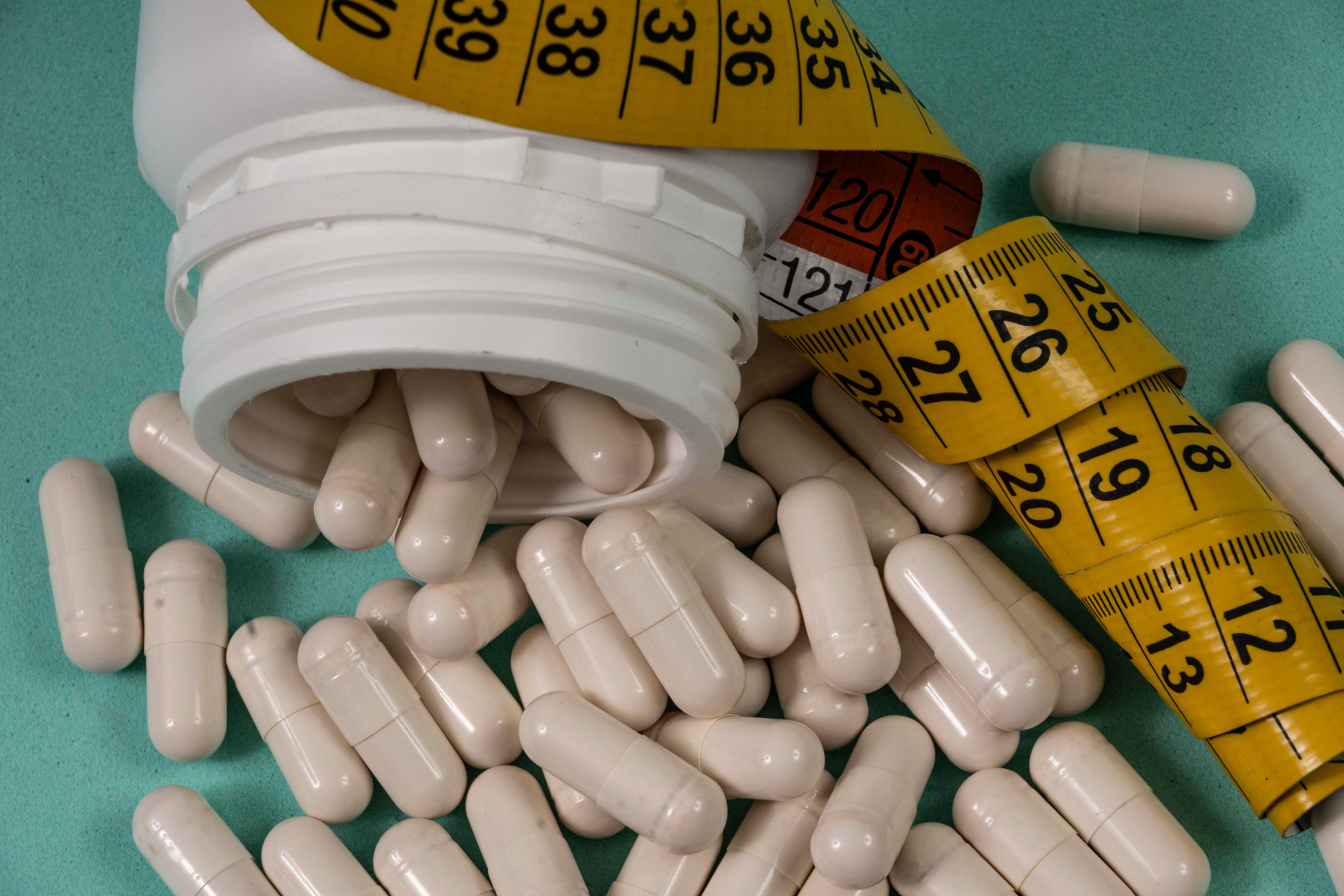 bottle of pills, some of which spilled onto a light blue surface - Image credit: Celso Pupo | stock.adobe.com