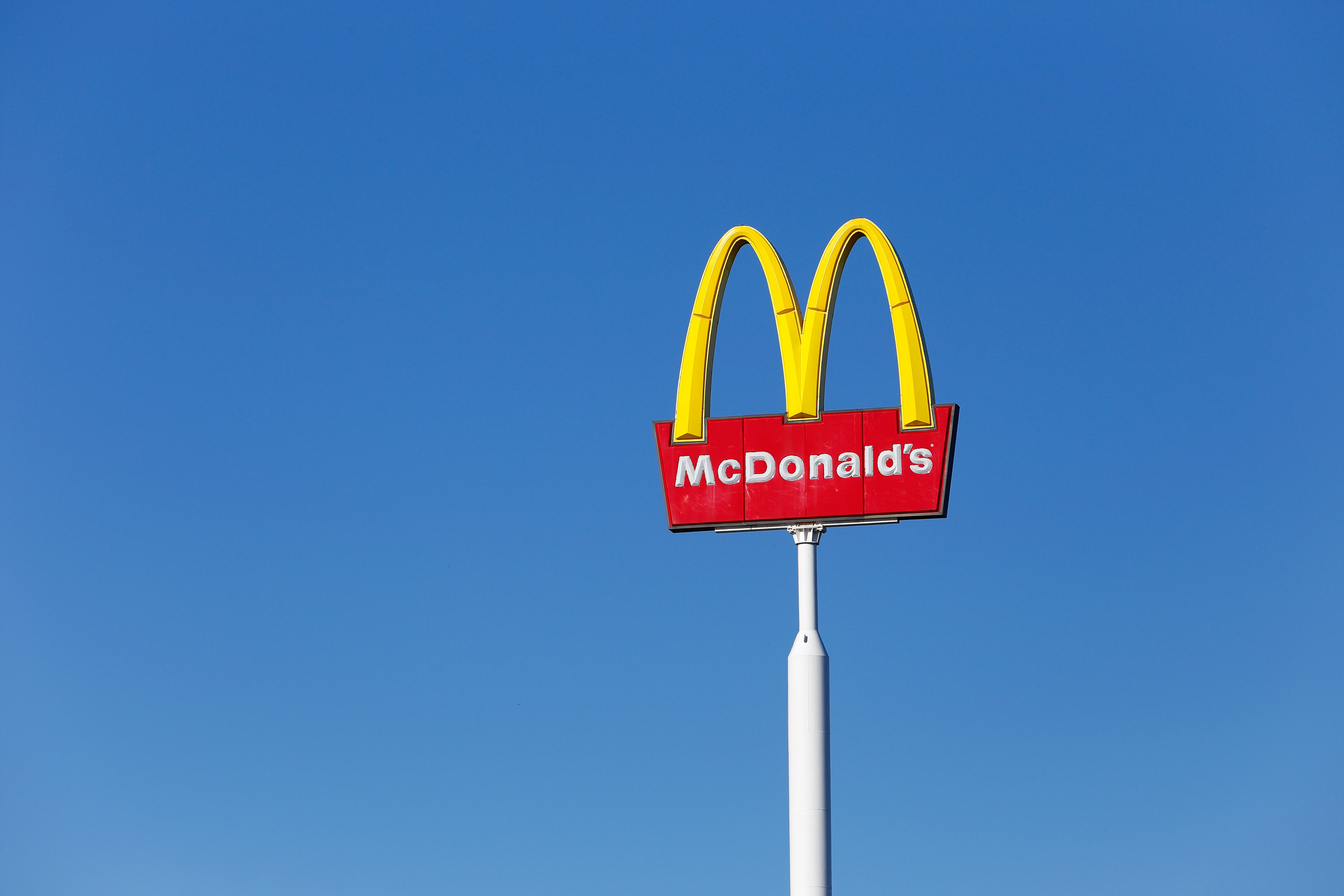 Sweden - March 23, 2015: McDonald's yellow and red logo advertising sign placed on a pole with against clear blue sky