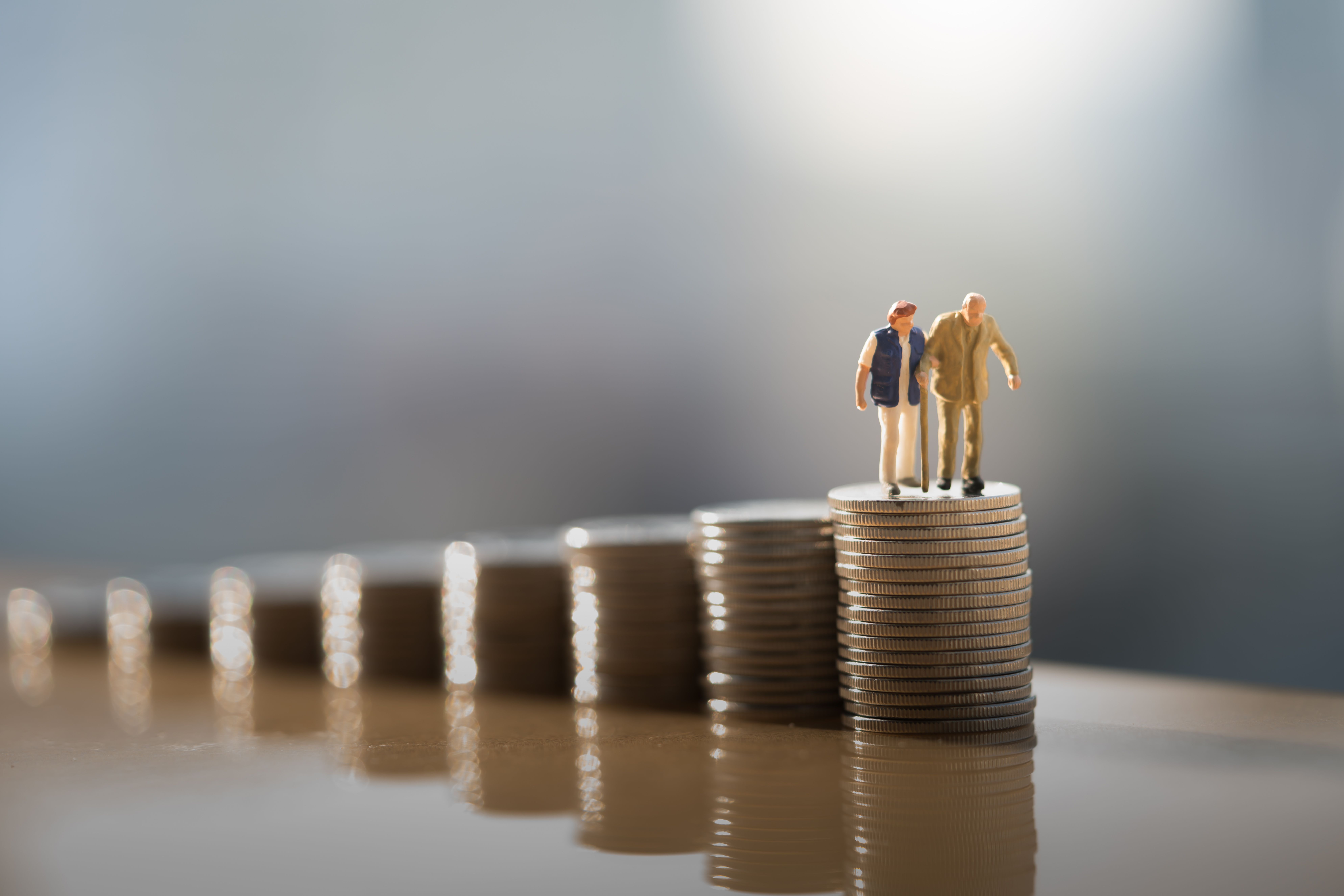Concept of retirement planning. Miniature people: Old couple figure standing on top of coin stack - Image credit: Khongtham | stock.adobe.com