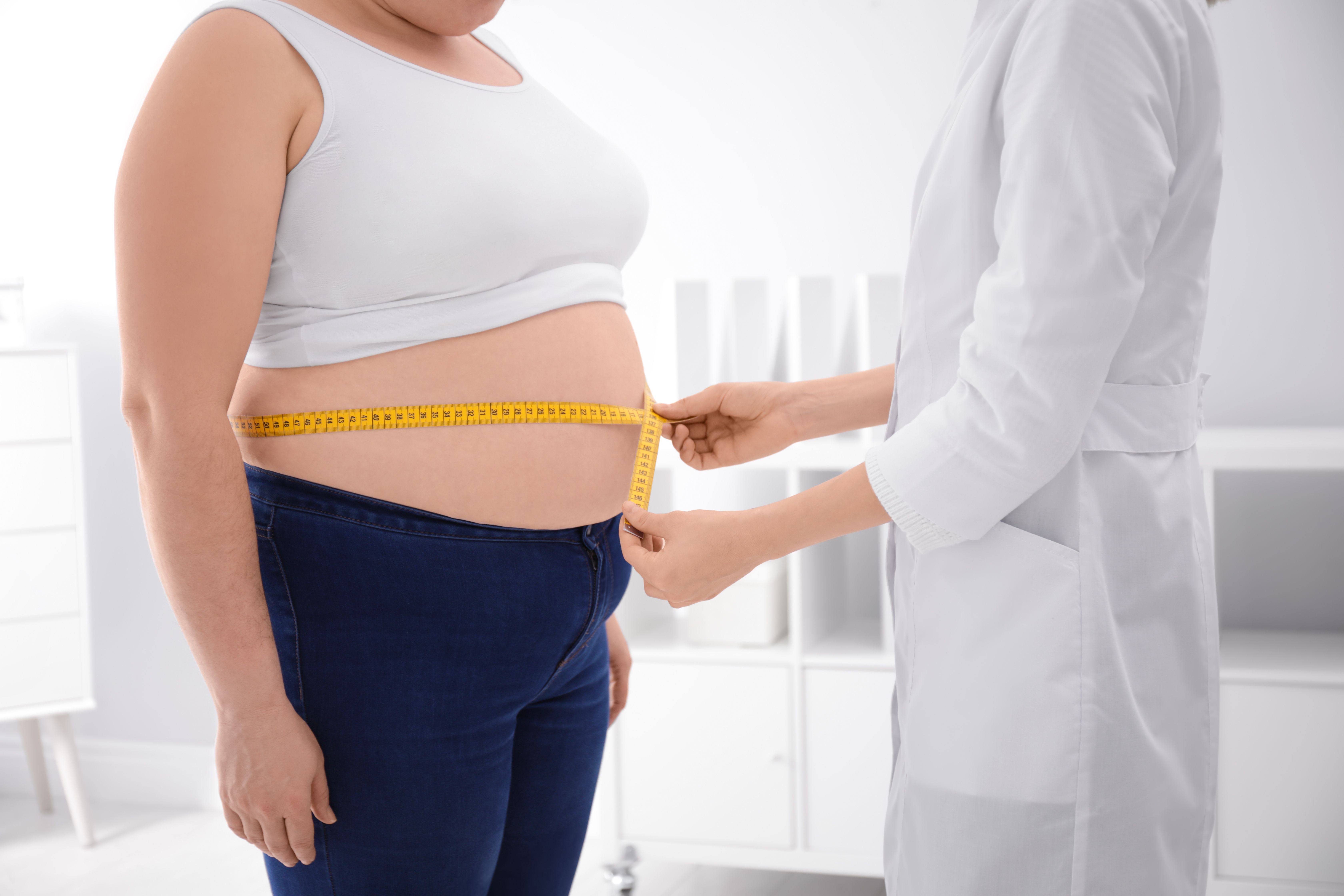 Doctor measuring waist of overweight woman in clinic, closeup - Image credit: New Africa | stock.adobe.com