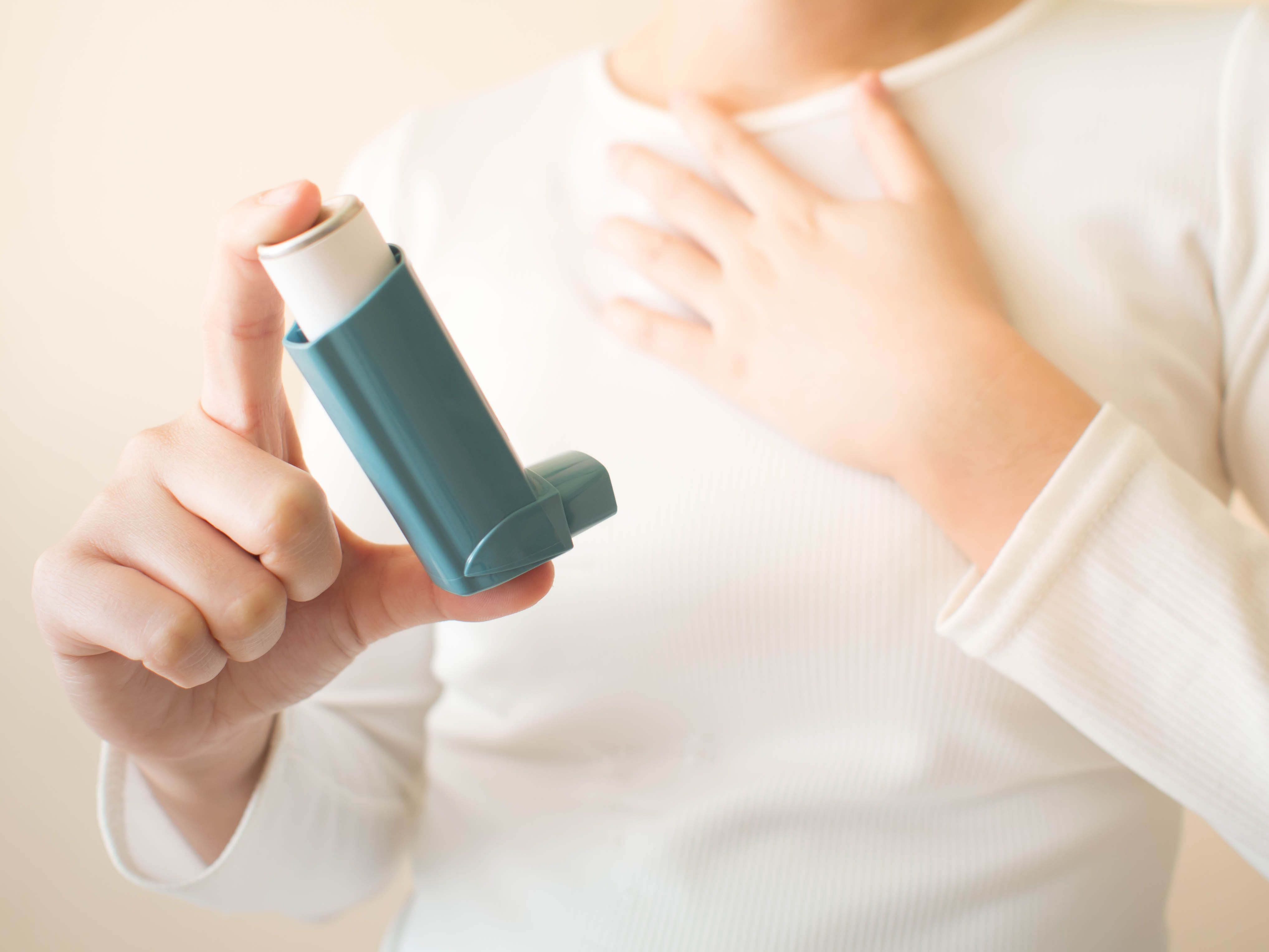 Young female in white t-shirt using blue asthma inhaler for relief asthma attack. Pharmaceutical products is used to prevent and treat wheezing and shortness of breath caused asthma or COPD - Image credit: Orawan | stock.adobe.com