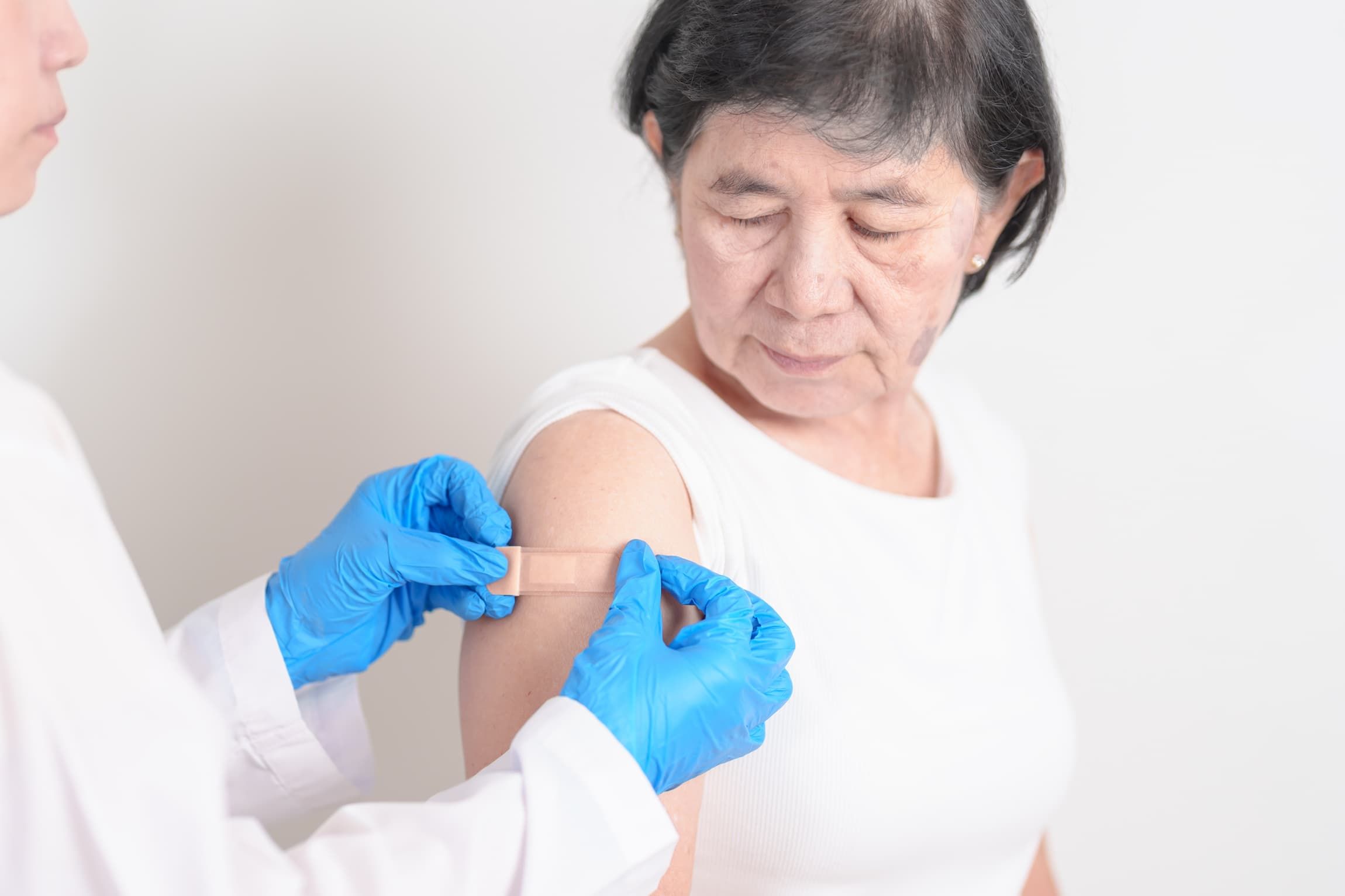Elderly Woman with bandage after received vaccine. Vaccination and Immunization for Influenza, Herpes Zoster, Tetanus, Covid 19 booster, Dengue, Encephalitis, Rabies, Pneumococcal, IPD, RSV Vaccines 