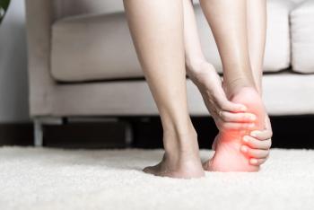 Woman standing feeling pain in her foot at home.