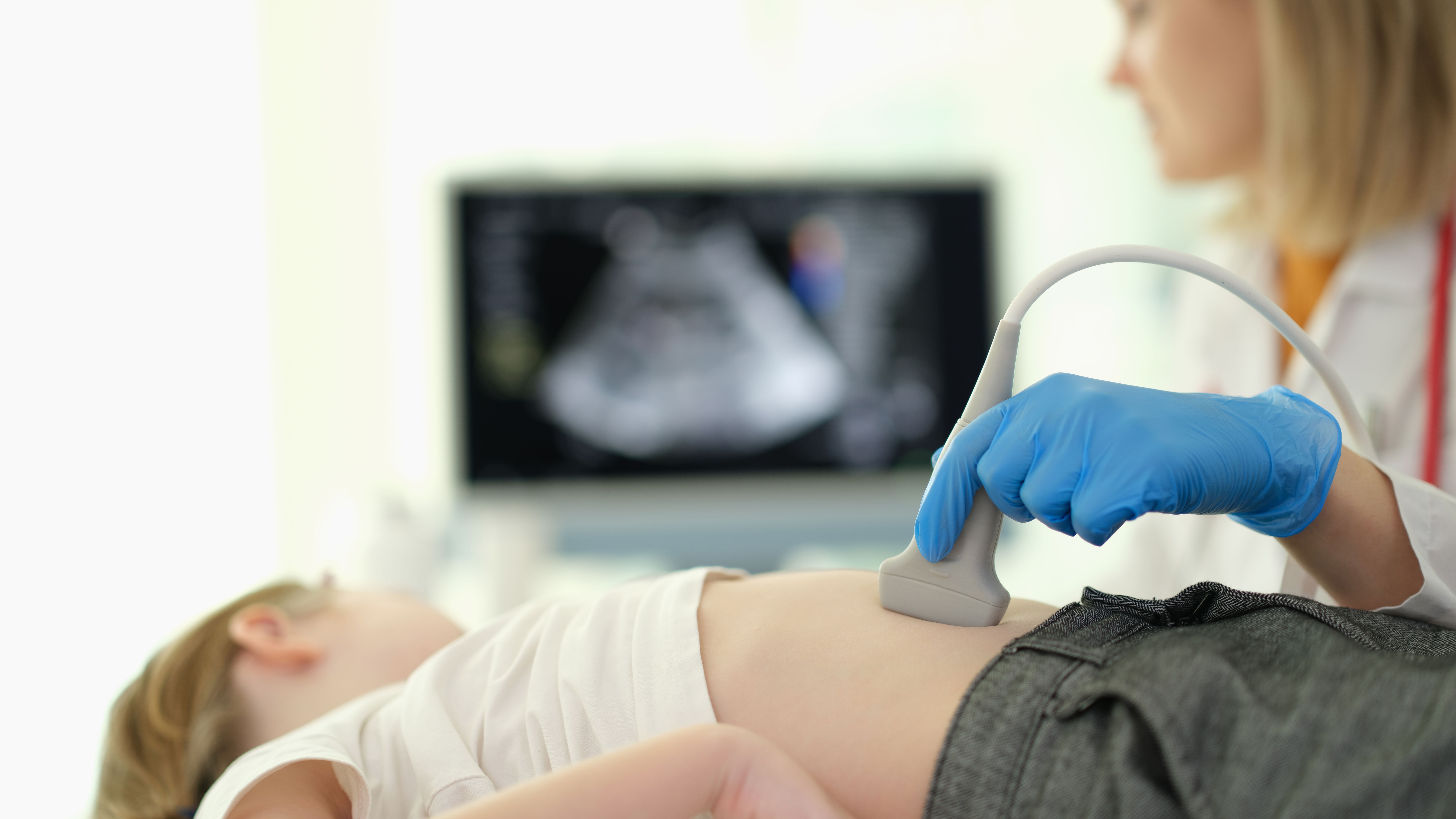Doctor gastroenterologist making ultrasound examination of liver and pancreas to child in clinic closeup. Diagnosis and treatment of diseases of internal organs in children concep - Image credit: H_Ko | stock.adobe.com