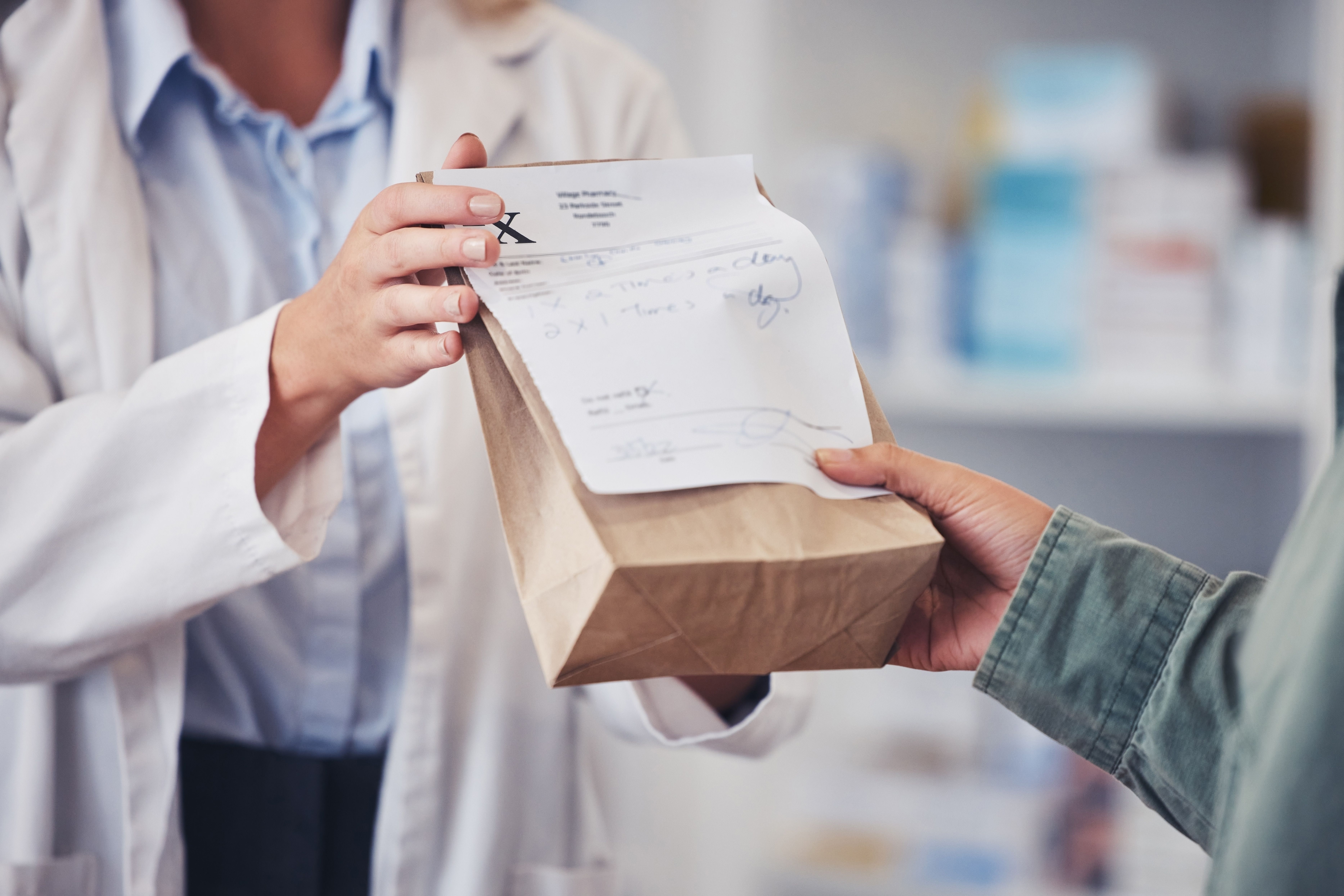 Pharmacy, hands and prescription medicine for customer with paper bag for healthcare, drugs and pharmaceutical. Closeup of a pharmacist or medical worker with person in drugstore for retail service - Image credit: Azee Jacobs/peopleimages.com | stock.adobe.com