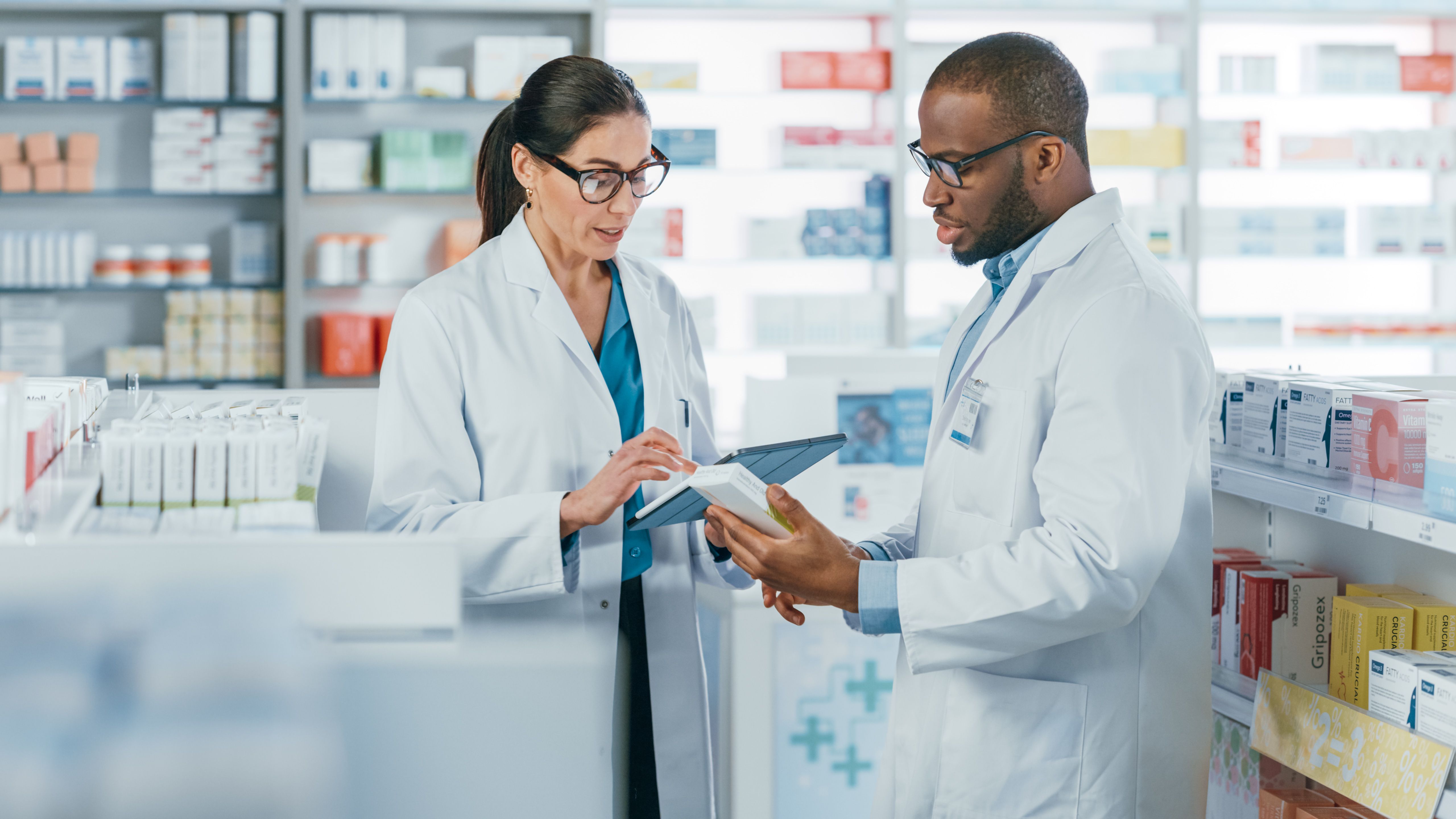 Pharmacy: Black Male and Female Pharmacists Use Digital Tablet Computer Talk about Medicine, Drugs, Vitamins, Supplements, Vaccine, Health Care Products. | Image Credit: Gorodenkoff - stock.adobe.com