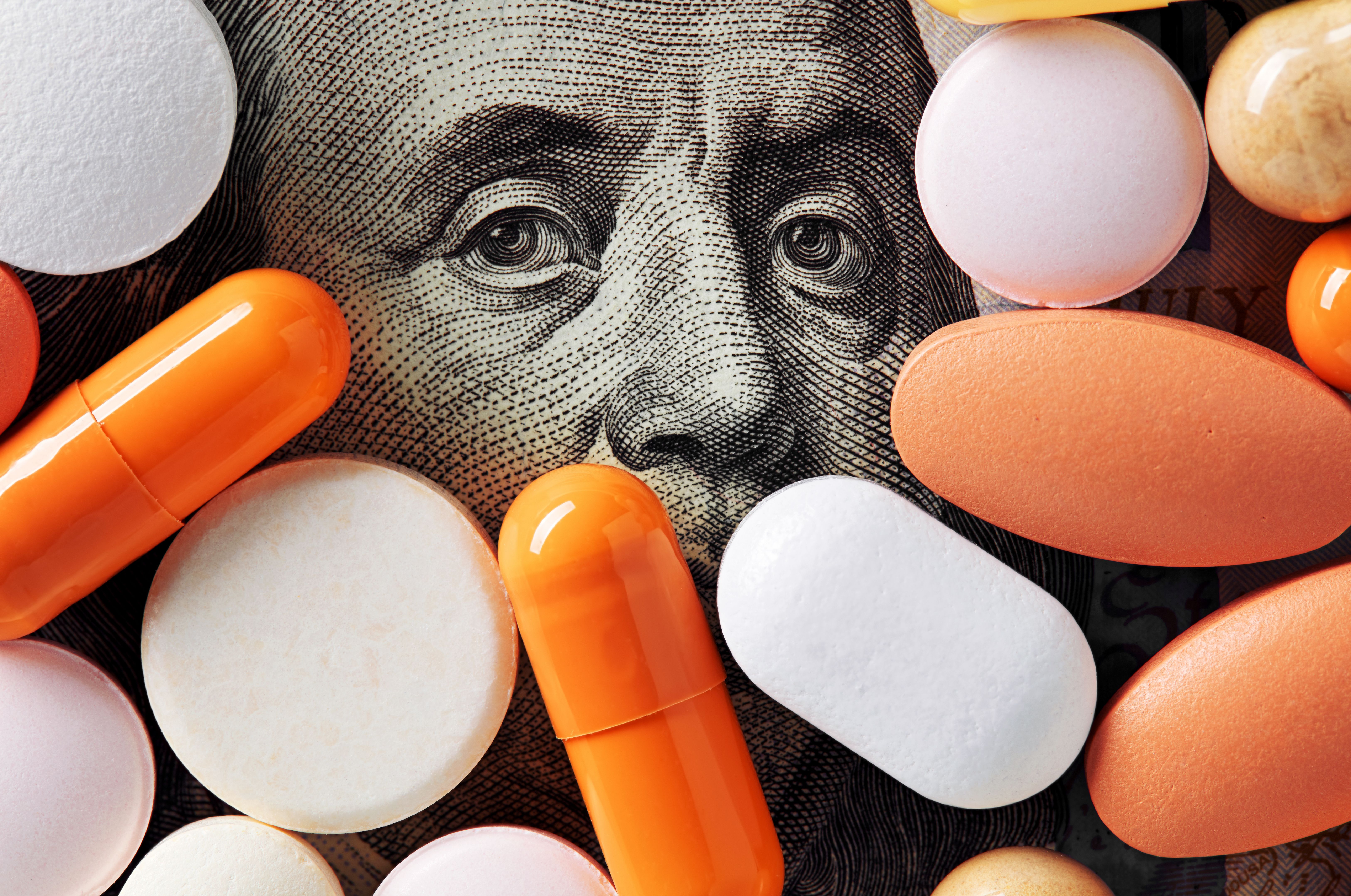 Benjamin Franklin on US dollar surrounded by pills | Image Credit: © Cagkan - stock.adobe.com